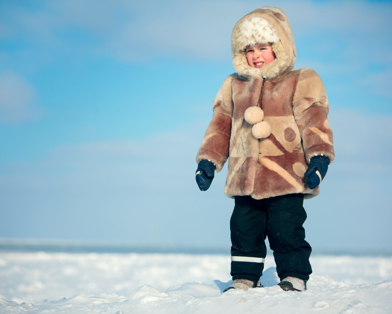 Маленький мальчик в теплой шубе на снегу 