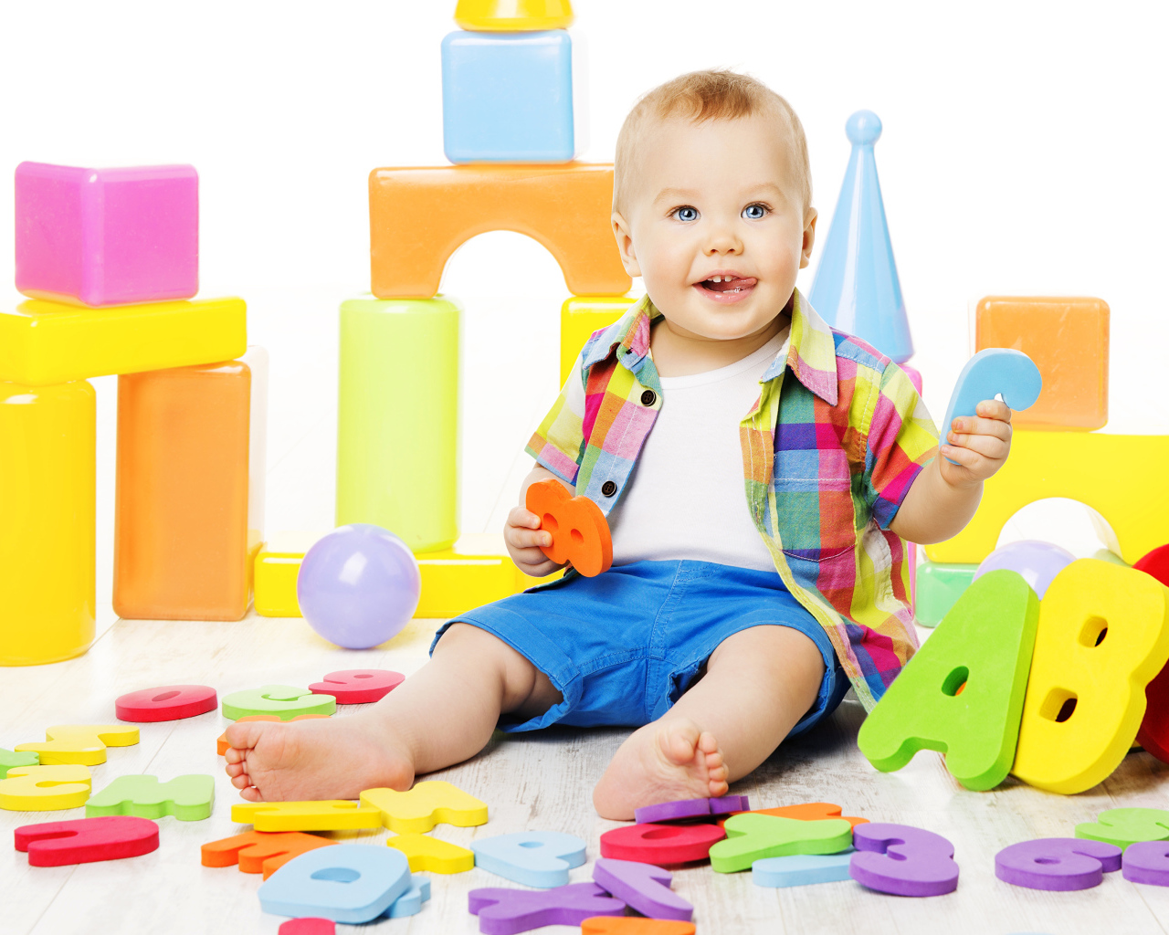 Маленький мальчик играет с разноцветными игрушками 