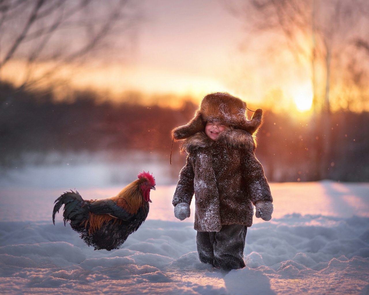 Маленький мальчик с петухом на снегу зимой