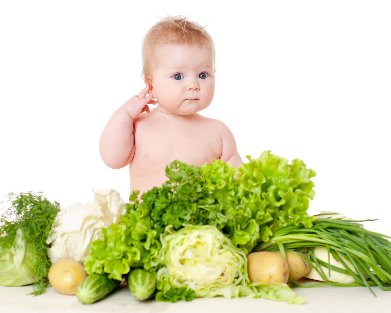 Маленький ребенок с овощами и зеленью на белом фоне