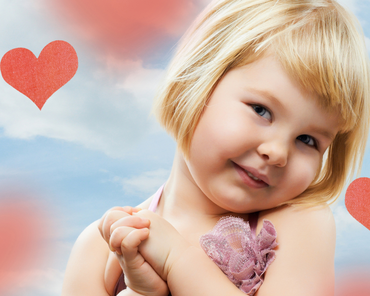Маленькая милая девочка на фоне красных сердечек