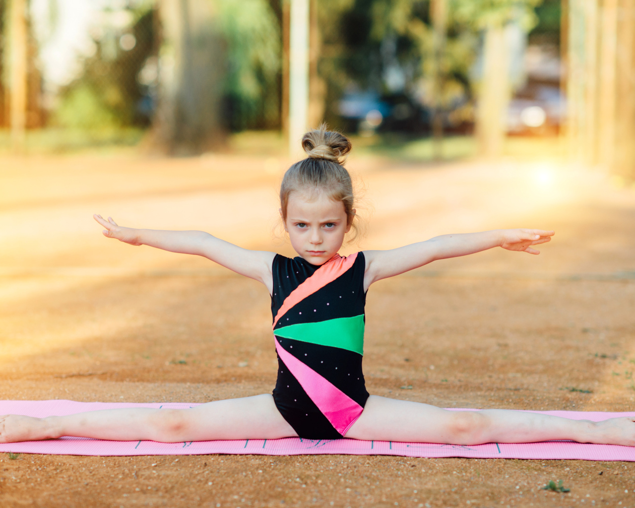 Маленькая девочка гимнастка сидит на шпагате 
