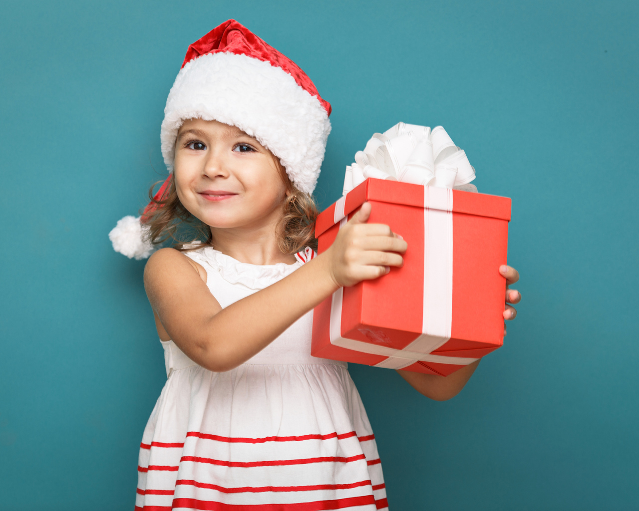 Маленькая девочка в новогоднем костюме с подарком на голубом фоне