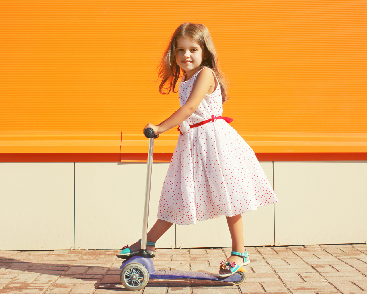 Маленькая девочка в платье на самокате 