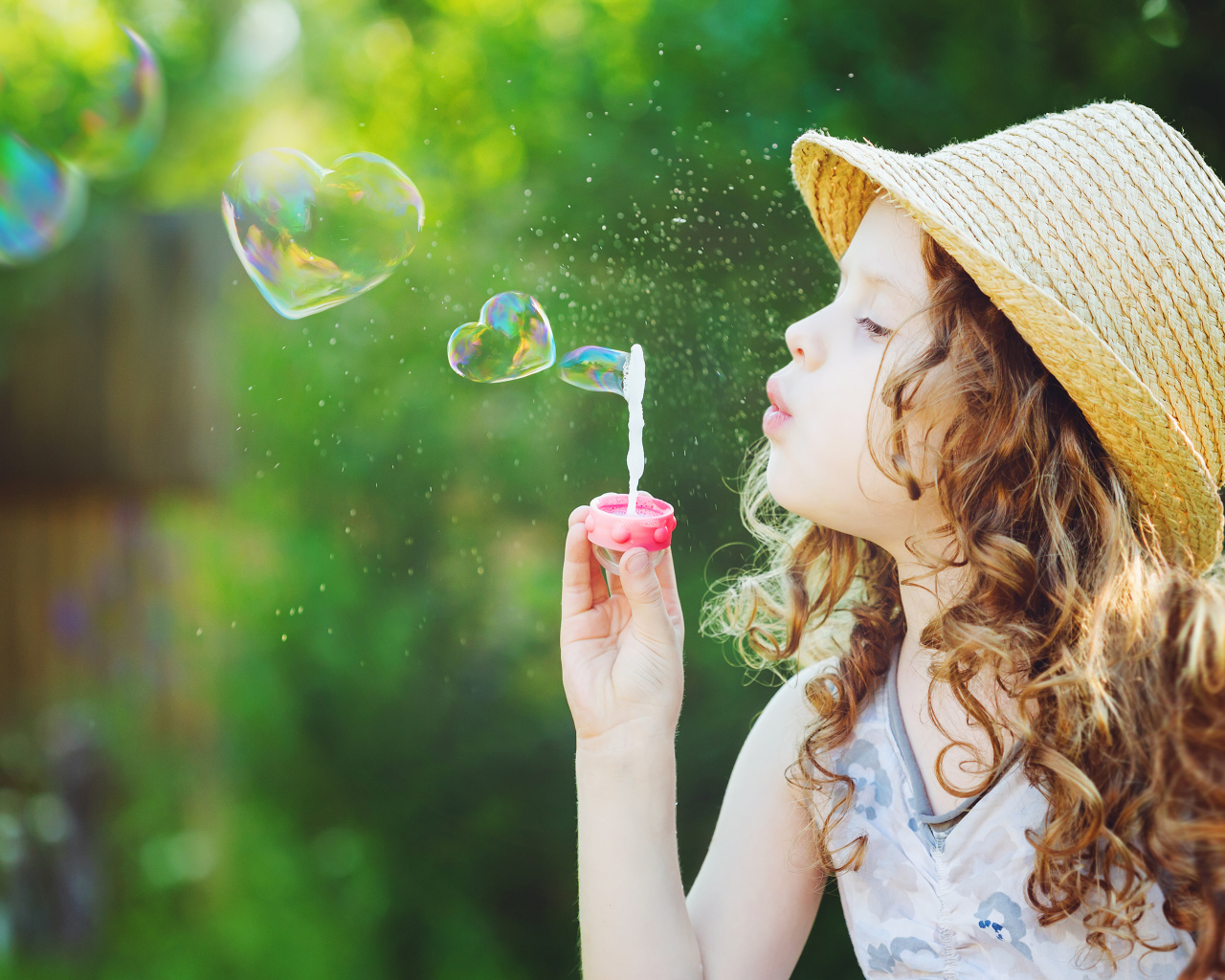 Маленькая девочка в шляпе с мыльными пузырями