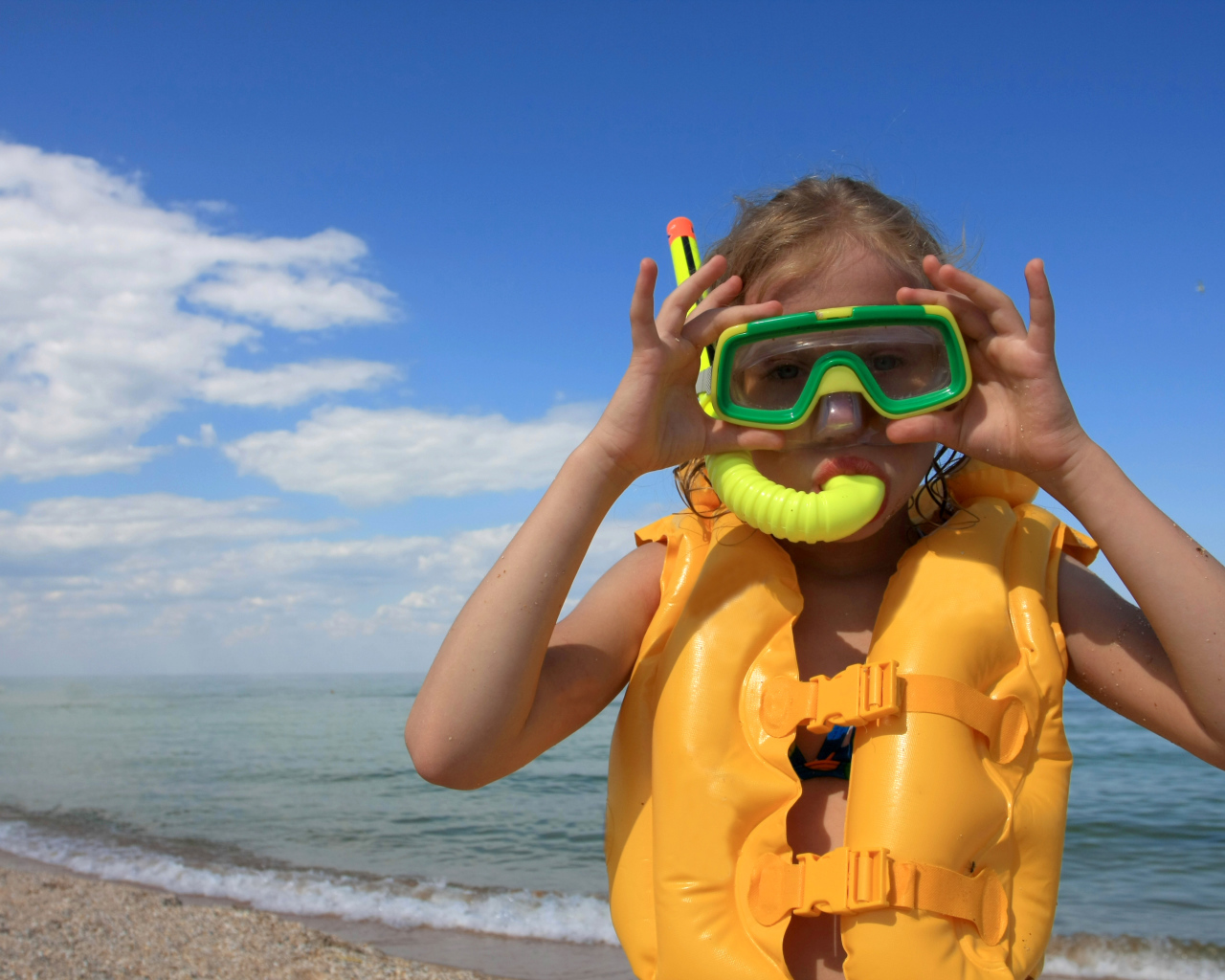 Маленькая девочка в маске и спасательном жилете на море