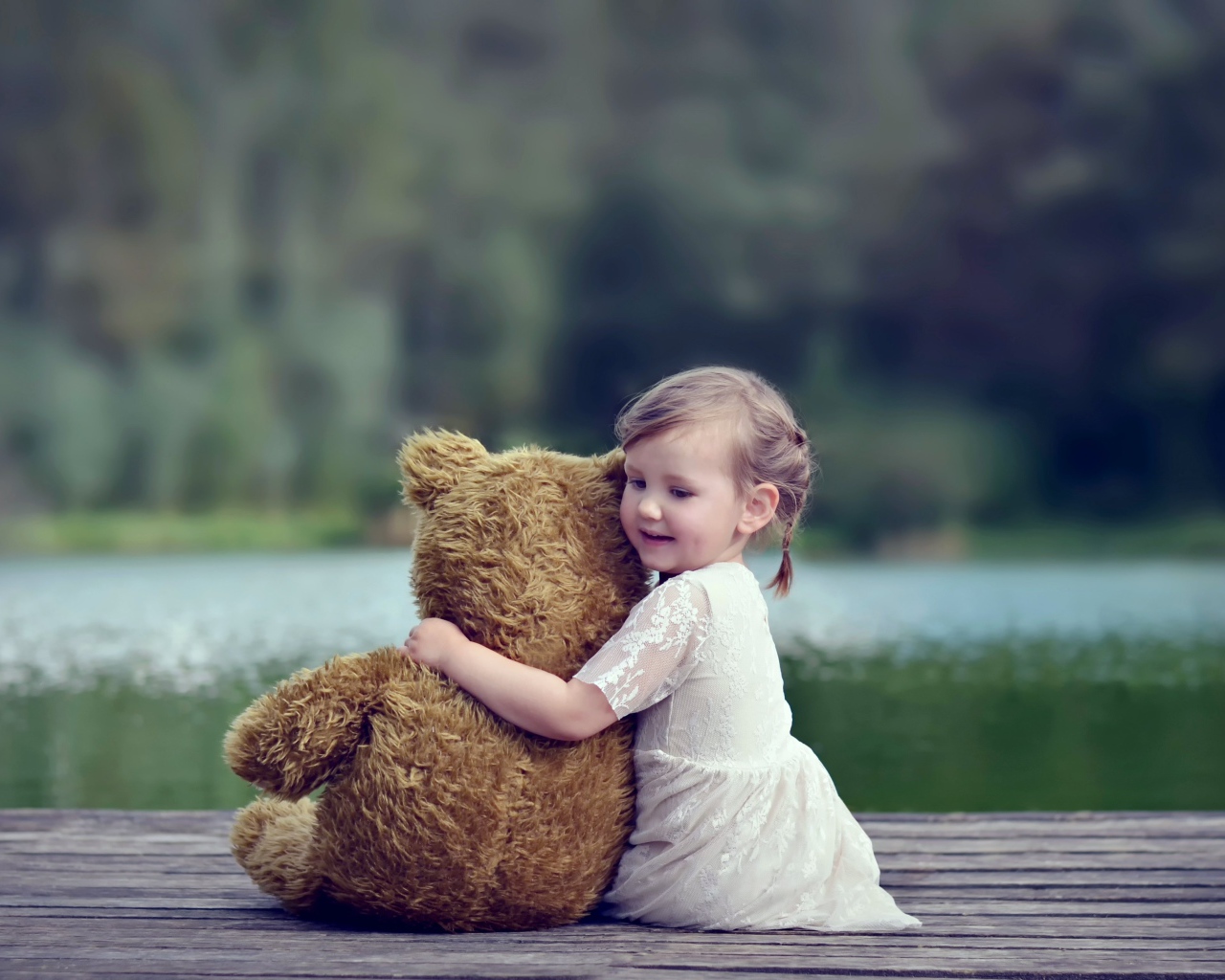 Маленькая девочка в белом платье сидит на мосту с плюшевым медведем