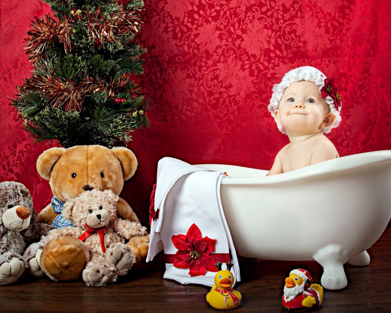 Маленькая девочка сидит в белой ванне у елки с игрушками