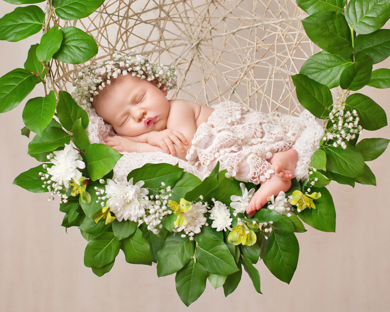 Маленькая девочка спит в колыбеле украшенной зелеными листьями