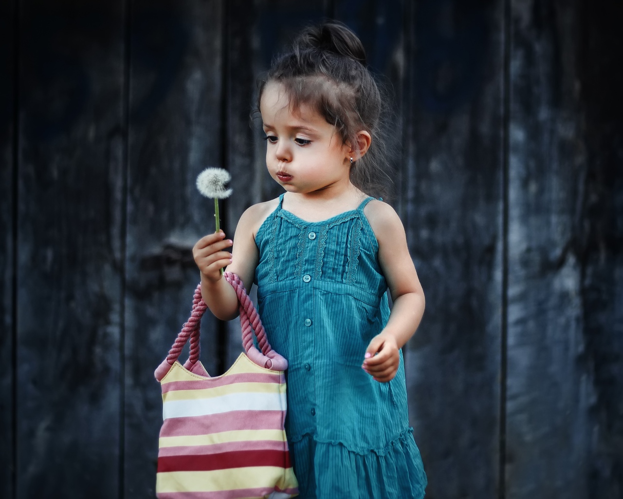 Маленькая девочка с сумкой и одуванчиком в руке