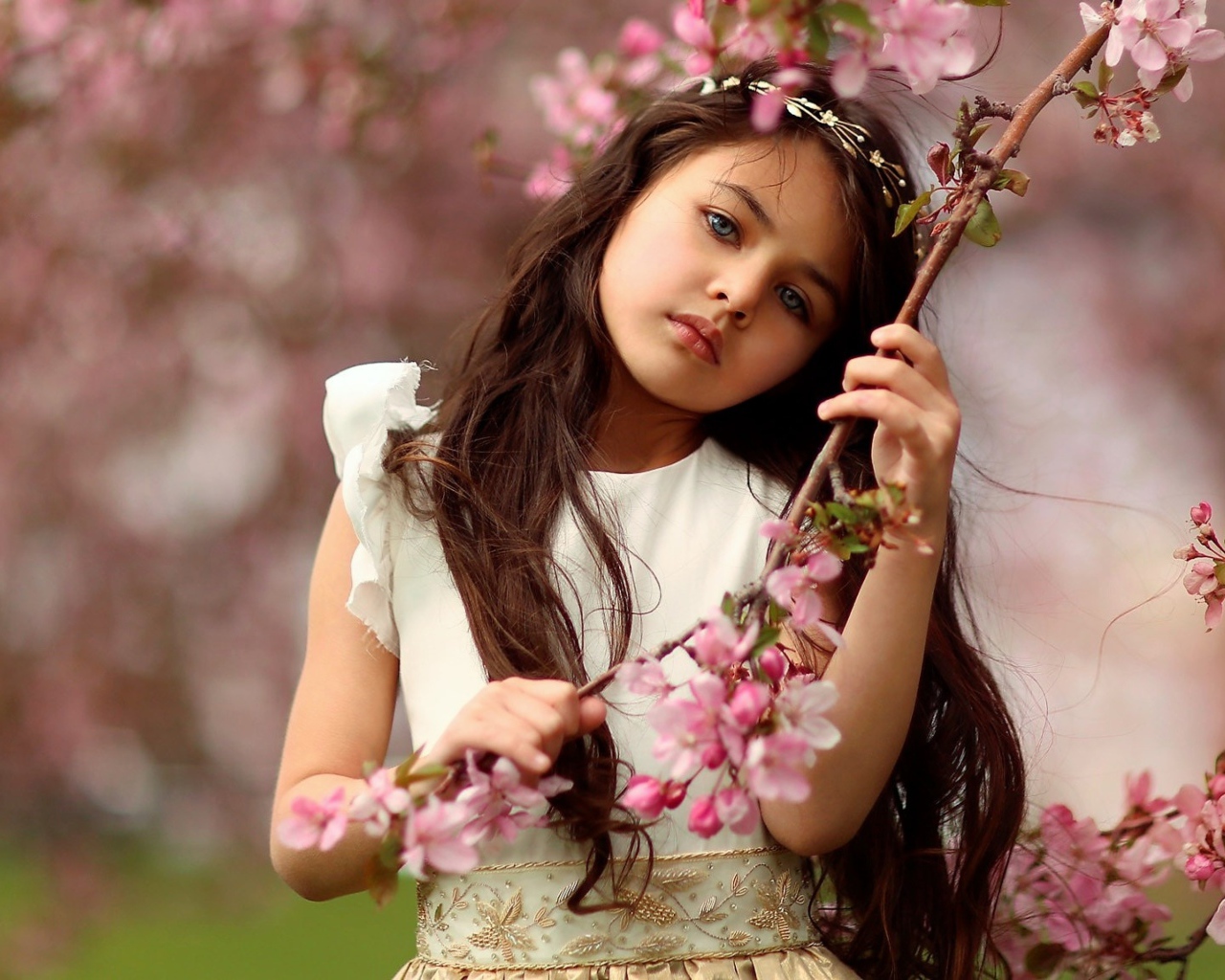 Маленькая девочка у цветущей розовыми цветами ветки