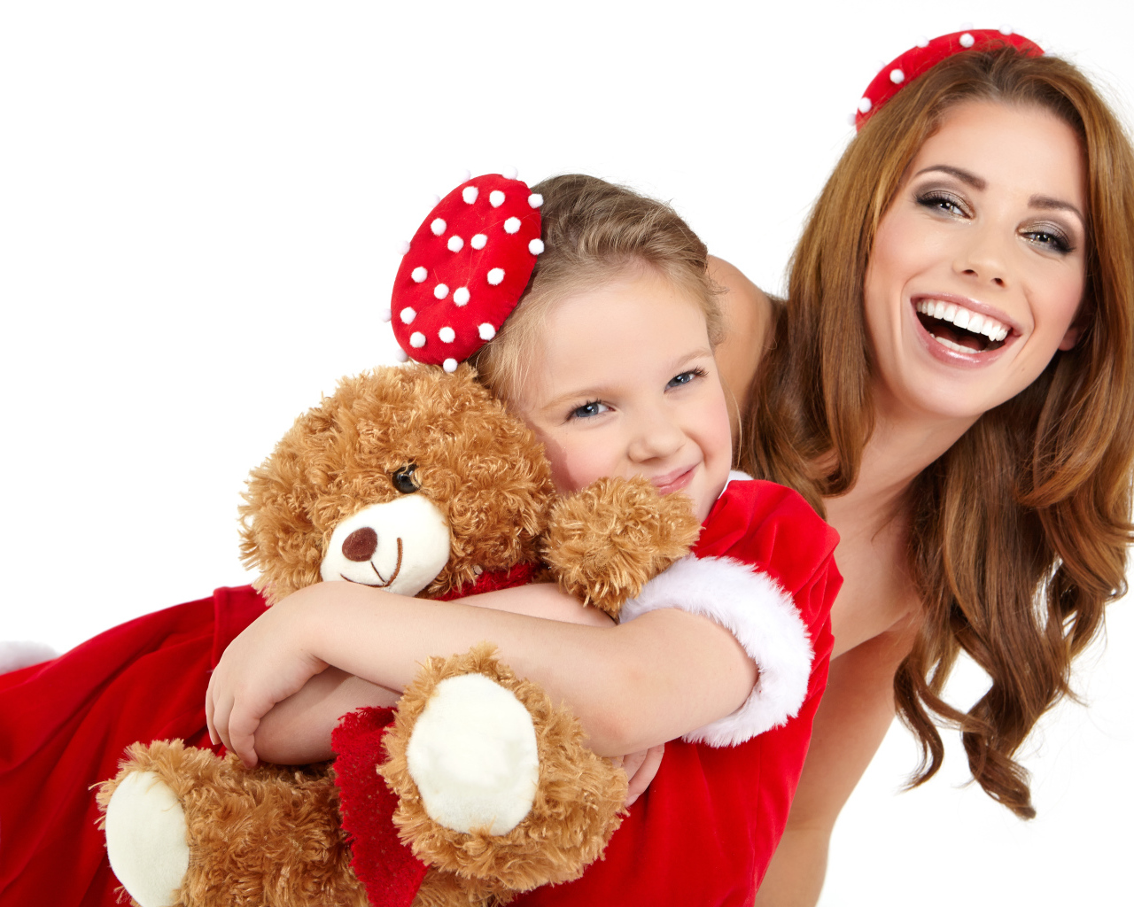 Маленькая девочка с мамой обнимает игрушечного медвежонка