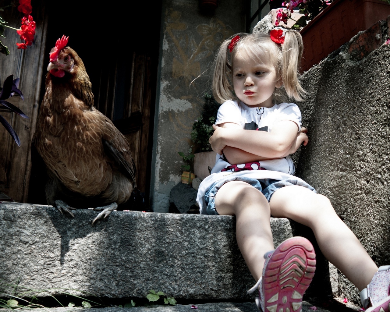 Маленькая обиженная девочка сидит на пороге с курицей