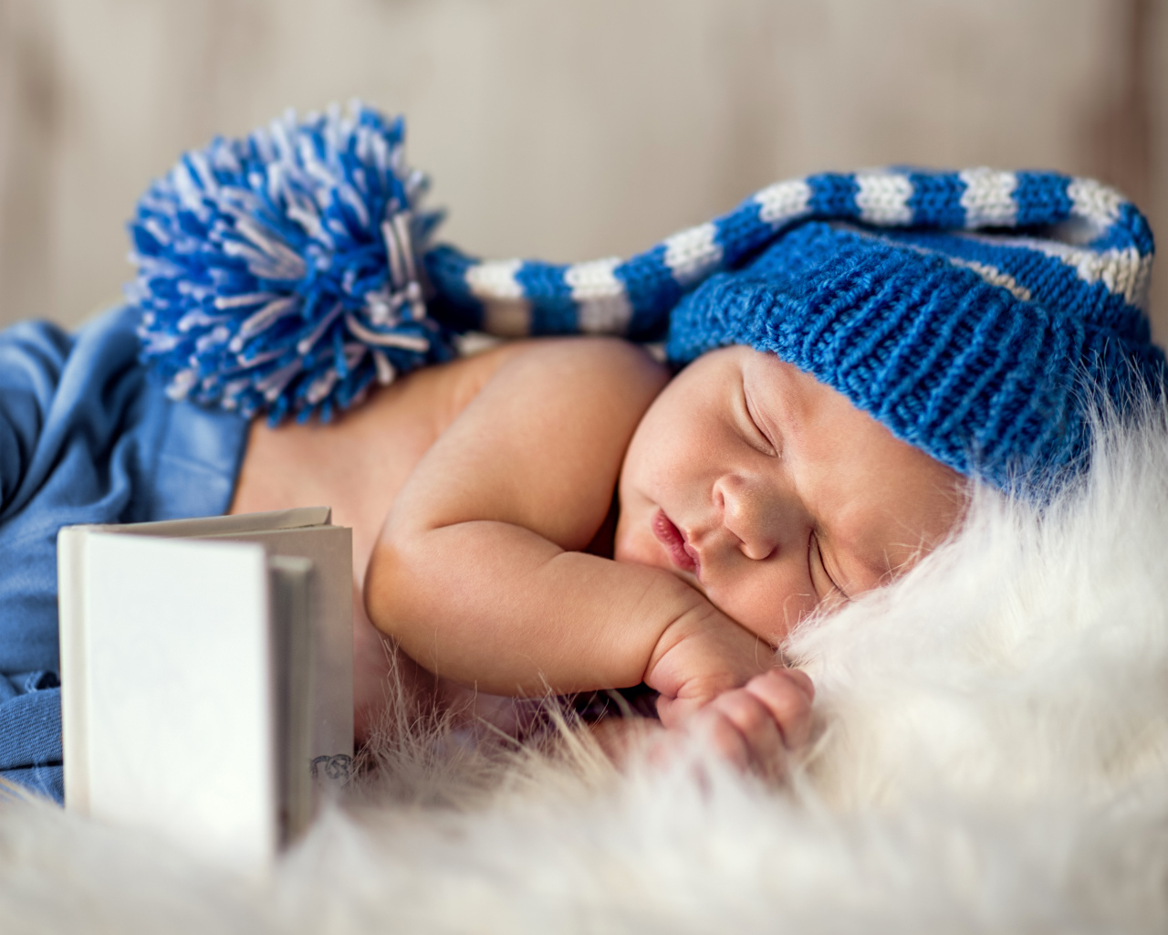 Маленький спящий грудной ребенок в синей вязанной шапке 