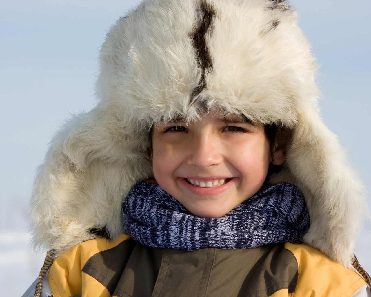 Маленький улыбающийся мальчик в теплой шапке зимой