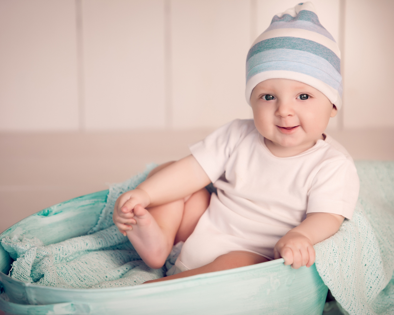 Маленький улыбающийся ребенок сидит в железном тазике