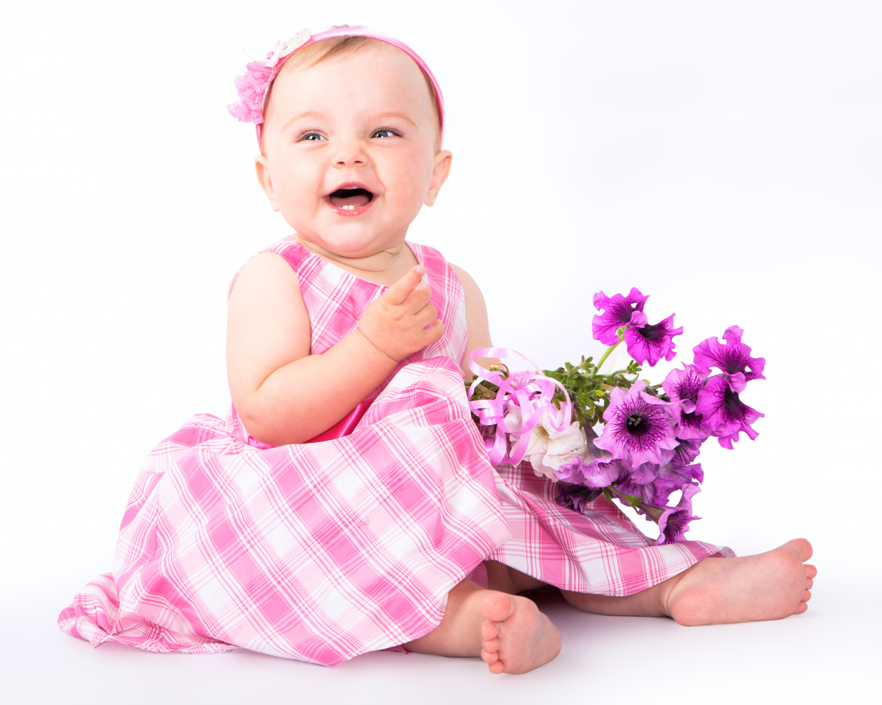 Маленькая улыбающаяся девочка с букетом петунии на белом фоне