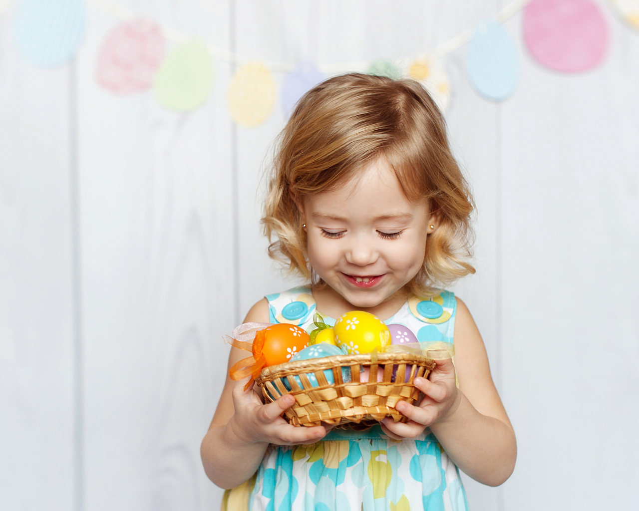 Маленькая улыбающаяся девочка с пасхальными яйцами в руках