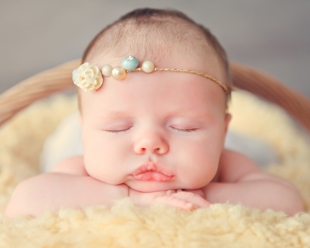 Спящая грудная девочка с красивым украшением на голове