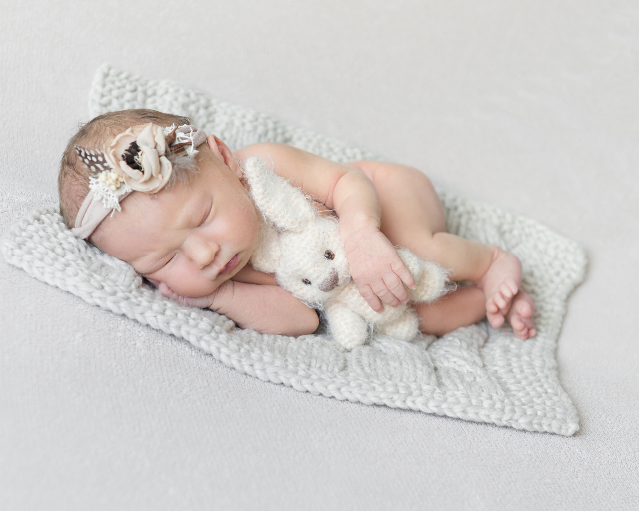 Спящий младенец с игрушкой на сером фоне 