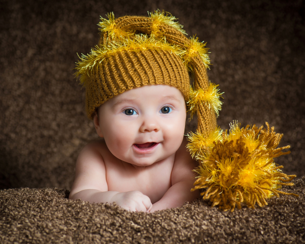 Улыбающийся малыш в красивой вязанной шапке 