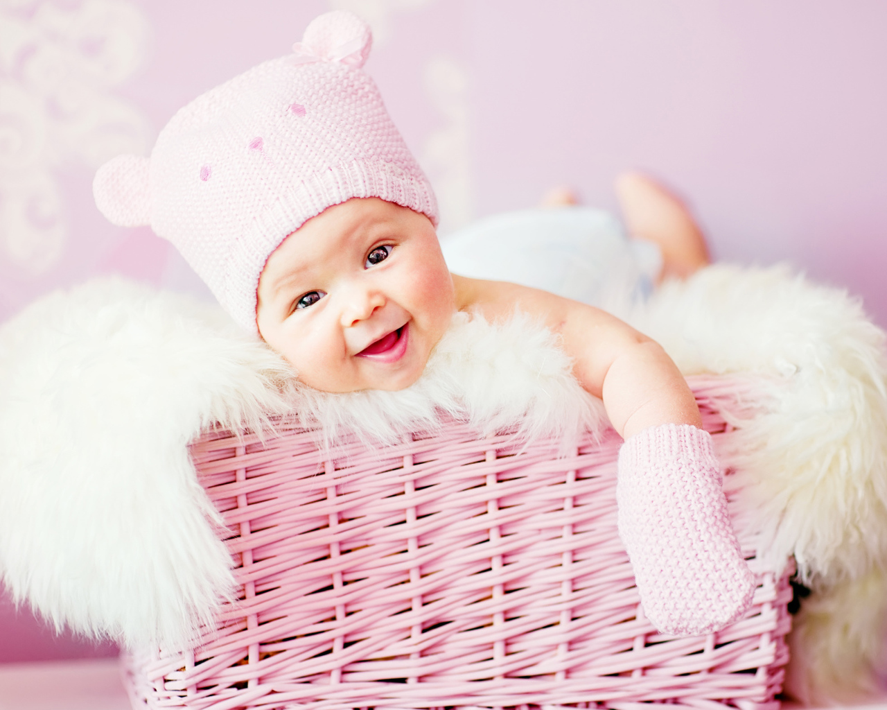 Улыбающийся грудной ребенок лежит в розовой корзине