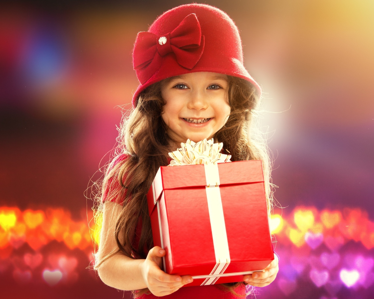 Улыбающаяся голубоглазая девочка с большим подарком в руках