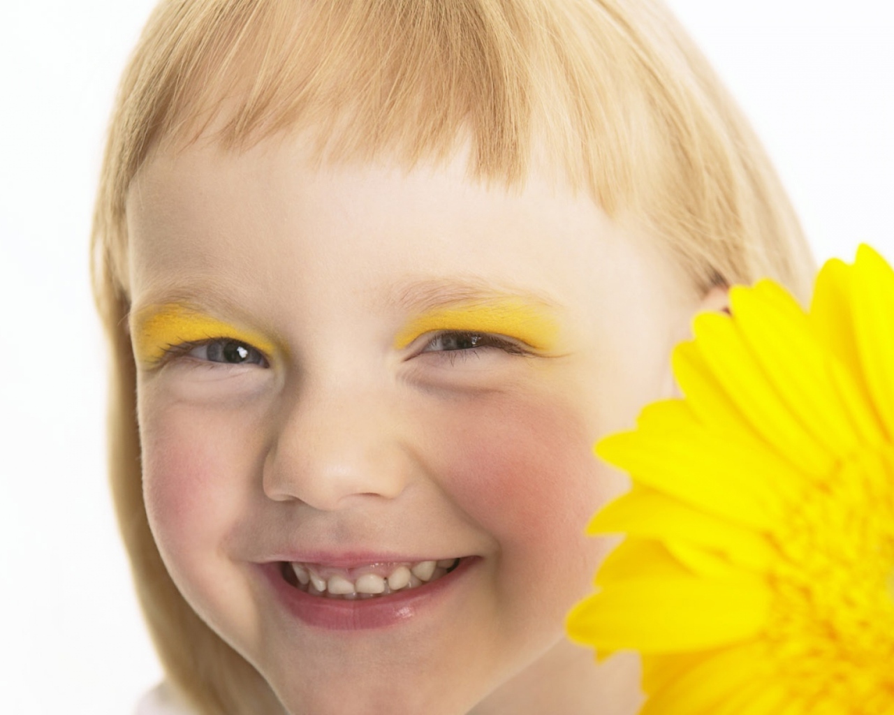 Улыбающаяся девочка с желтым цветком герберы