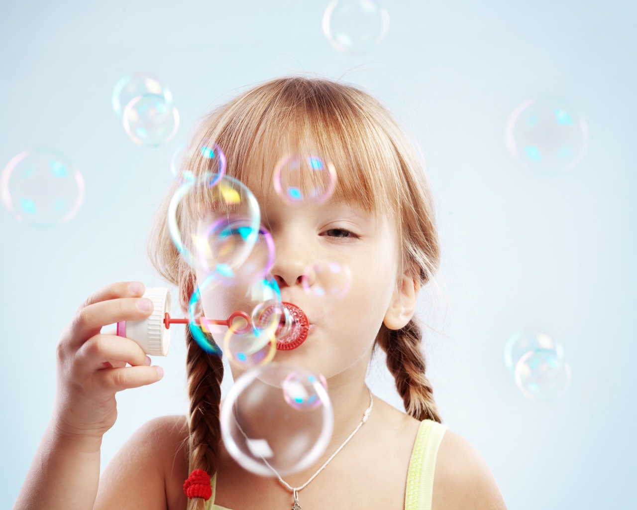 Девочка с косичками пускает мыльные пузыри