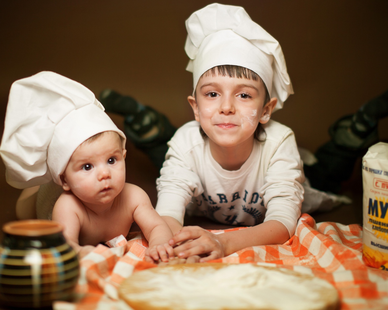 Два маленьких мальчика в шапках повара на кухне