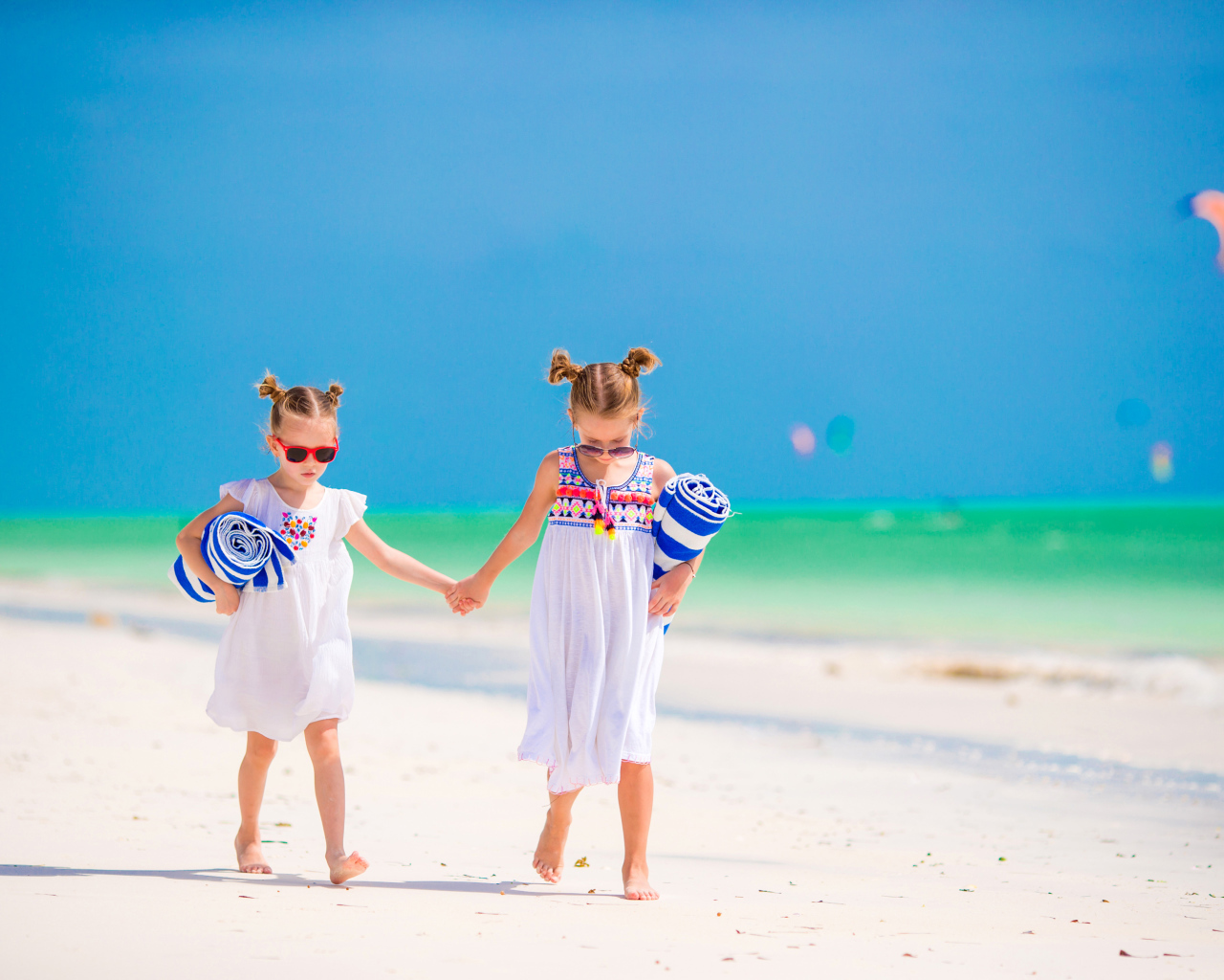 Две маленькие девочки идут по песку