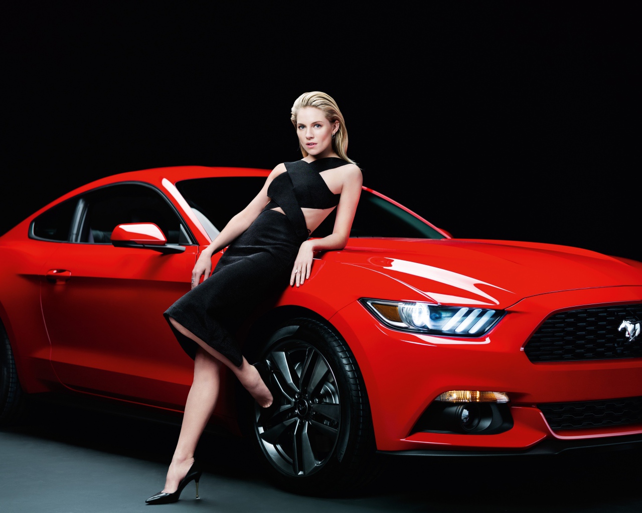 Актриса Сиенна Миллер в черном платье у красного автомобиля Ford Mustang