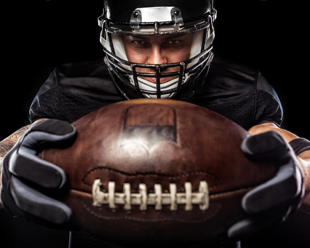 Американский футболист с мячом на черном фоне