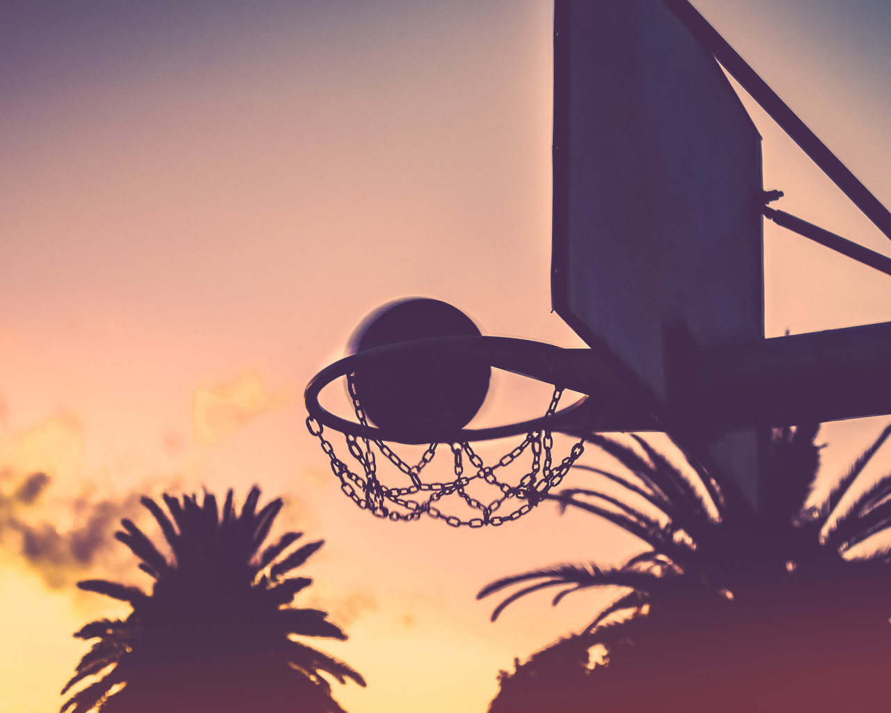 Баскетбольное кольцо с мячом на закате