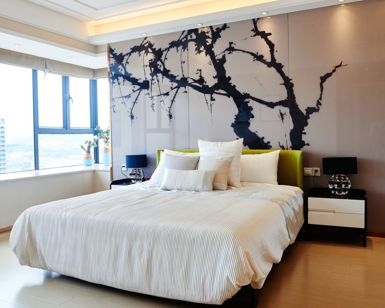 Красивая светлая спальня с большой кроватью и рисунком на стене 