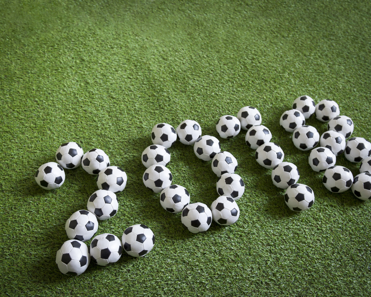 Цифры 2018 из футбольных мячей на зеленой траве