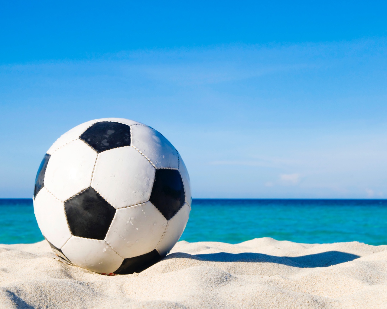 Футбольный мяч на белом песке на фоне голубого неба