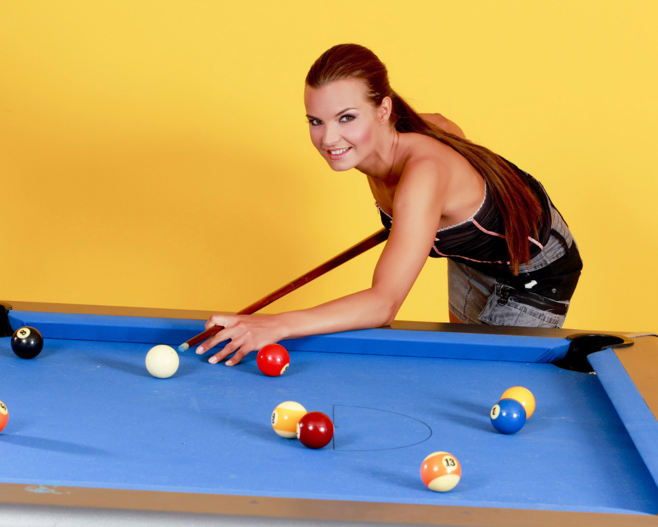 Молодая девушка играет в бильярд