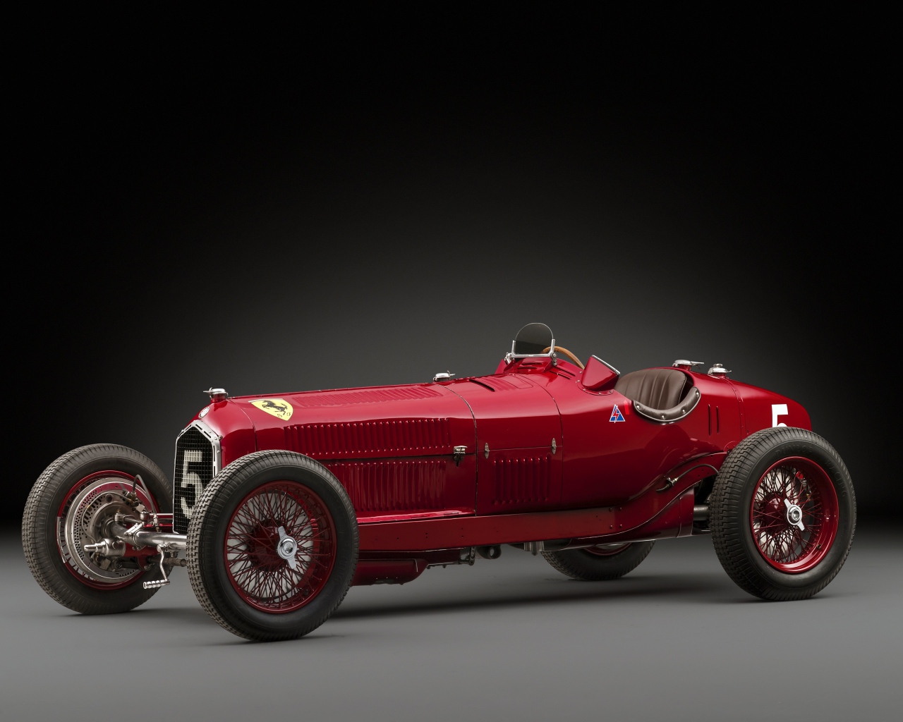 Красный ретро автомобиль Alfa Romeo на сером фоне