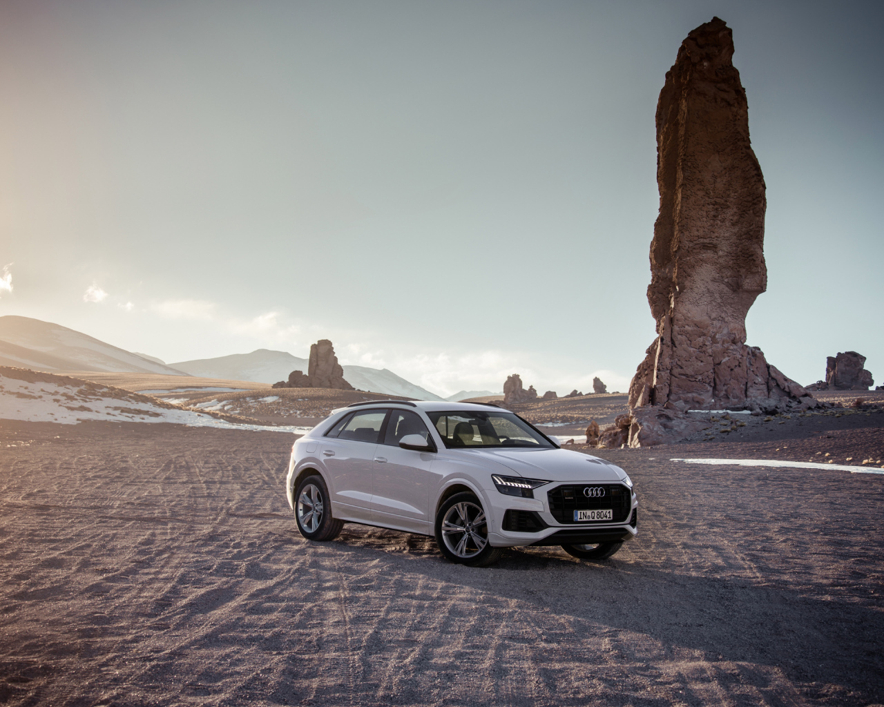 Audi Q8 SUV stands on the sand against the backdrop of rocks