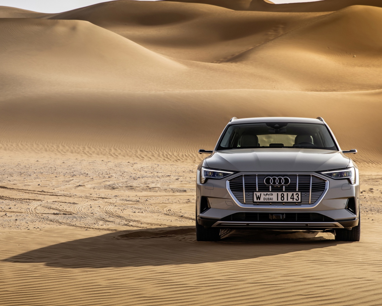 Серебристый автомобиль Audi E-tron Quattro в пустыни