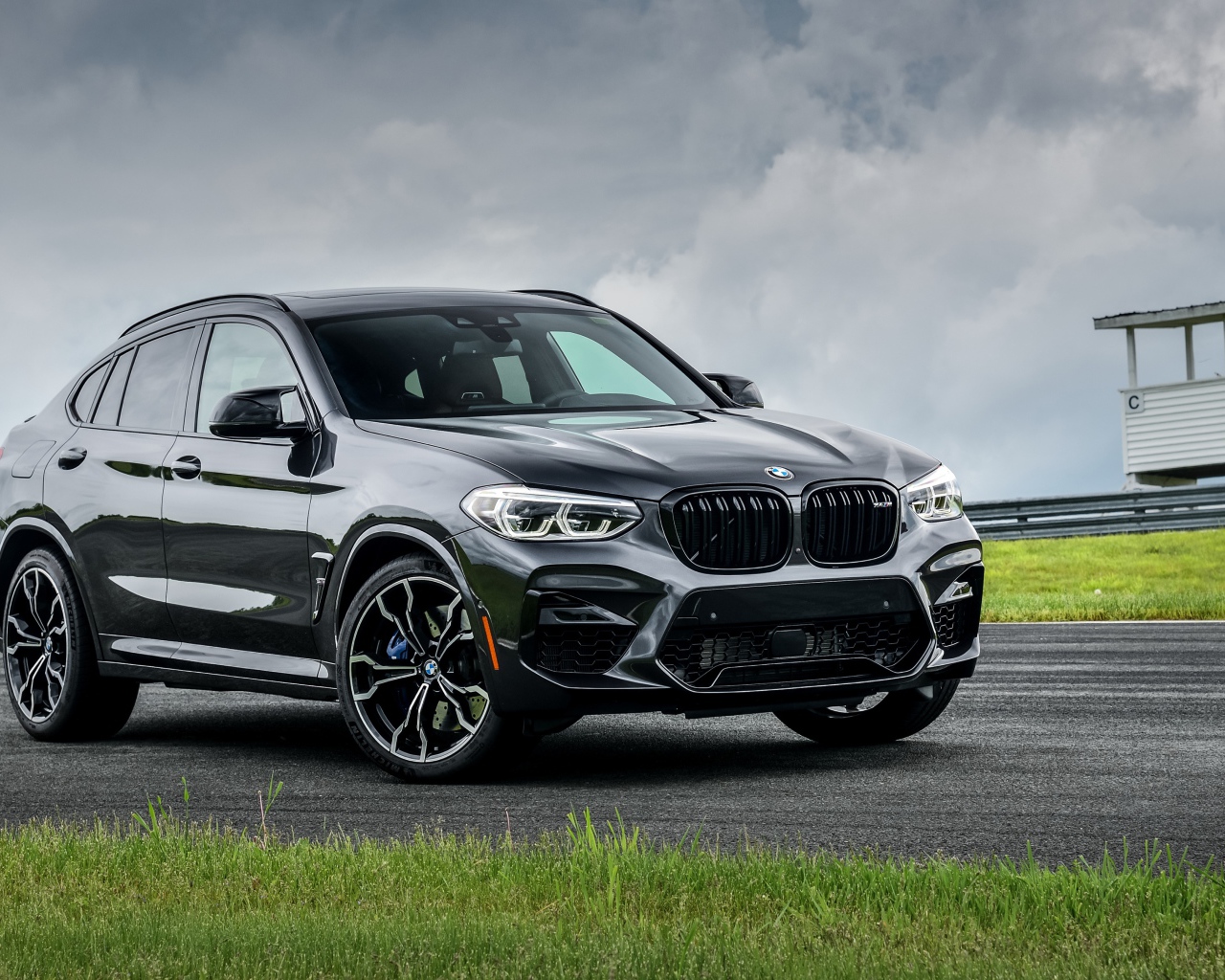 Черный автомобиль  BMW X4 M Competition, 2020 года на фоне грозового неба