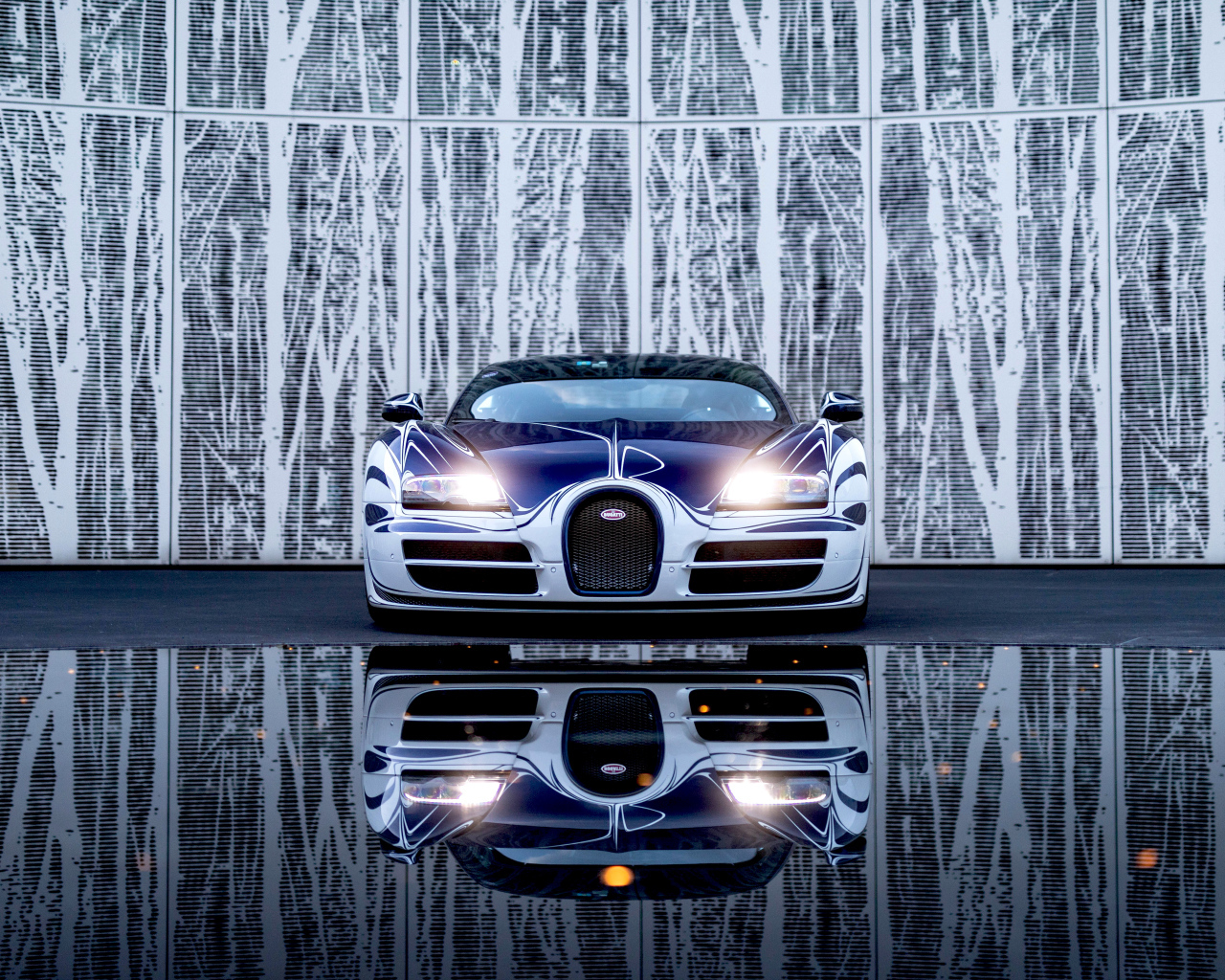 Автомобиль Bugatti Veyron Grand Sport Roadster отражается в зеркальной поверхности 