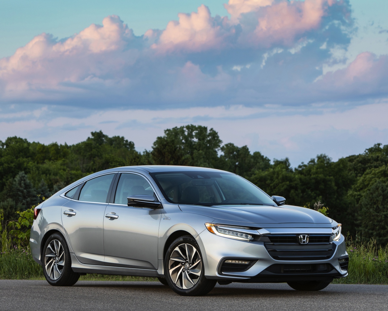 Серебристый автомобиль Honda Insight на фоне леса