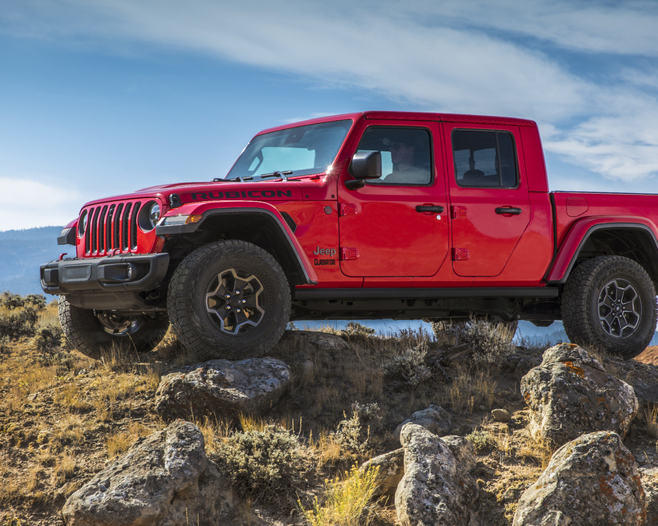 Красный пикап Jeep Gladiator Rubicon на холме с камнями