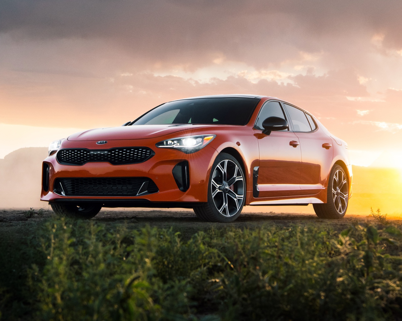 Оранжевый автомобиль  Kia Stinger GTS, 2020 года на закате