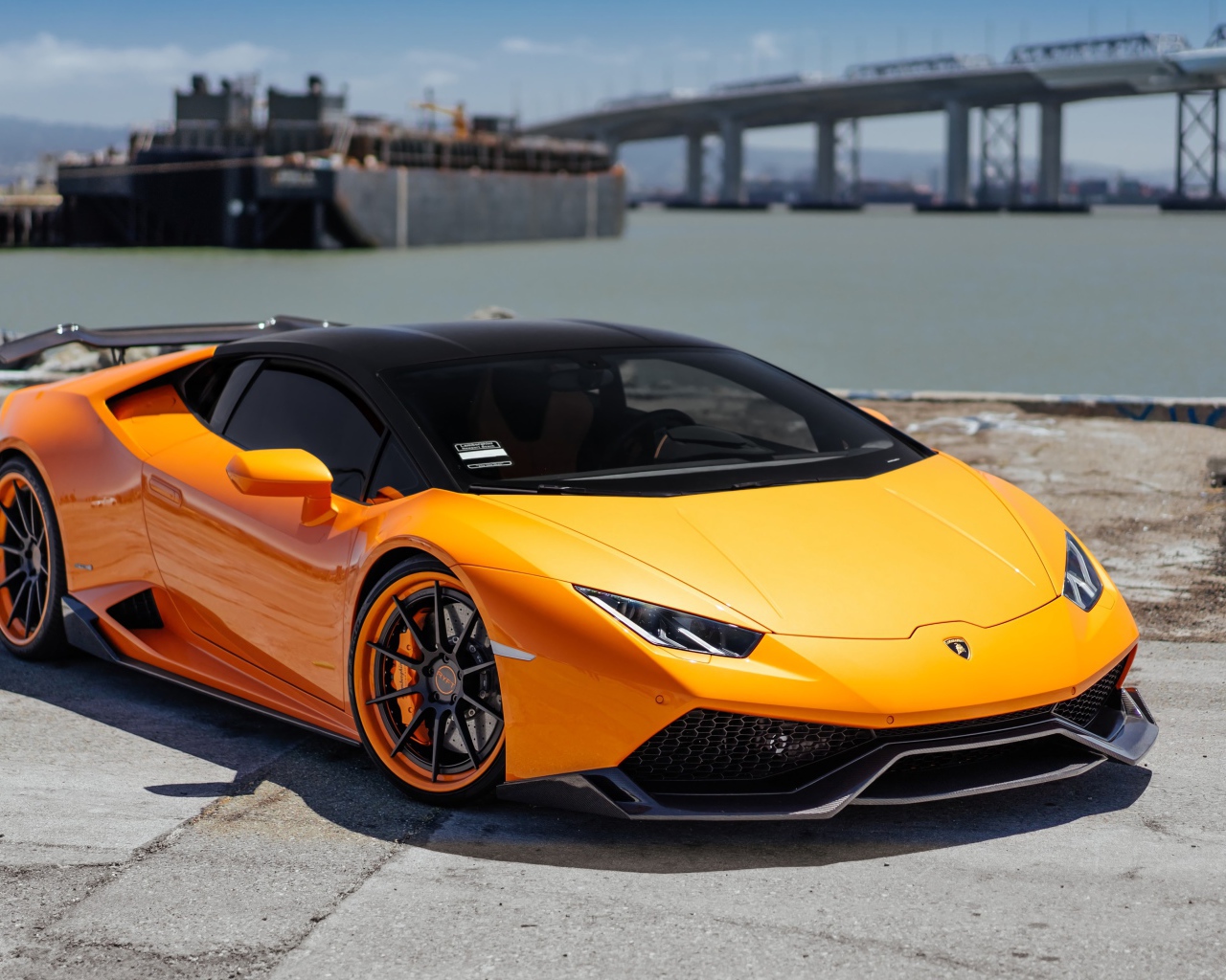 Оранжевый быстрый Lamborghini Huracan в порту у воды