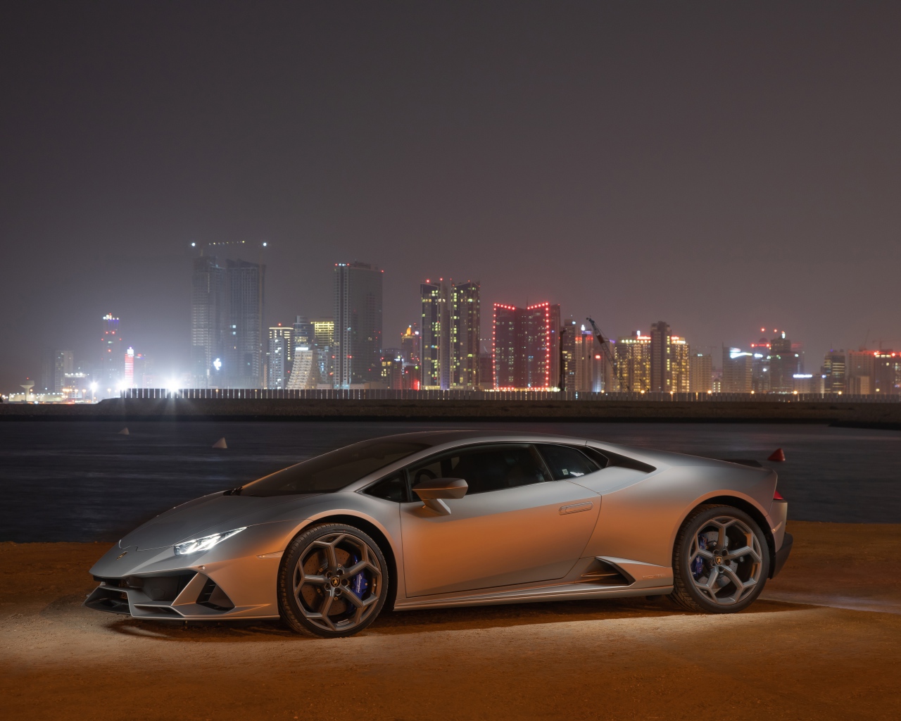 Серебристый автомобиль Lamborghini Huracan Evo на фоне города