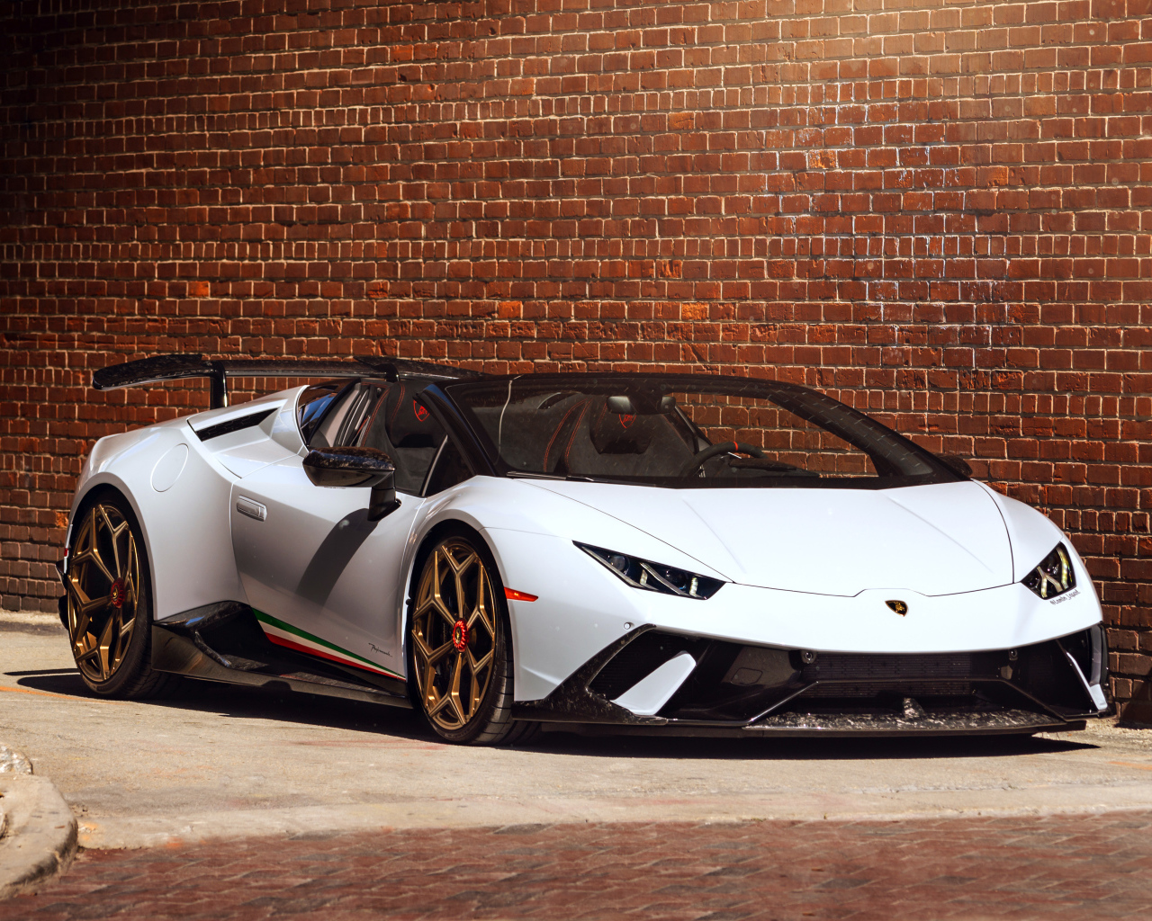 Белый быстрый Lamborghini Huracan стоит у кирпичной стены