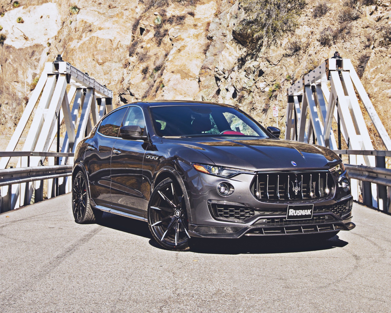 Внедорожник Maserati Levante на мосту на фоне гор